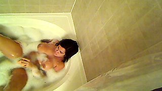 Busty brunette mom fucks herself with a toy in the bathtub