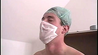 Girl in ponytails kneels to suck off a surgical masked doctor